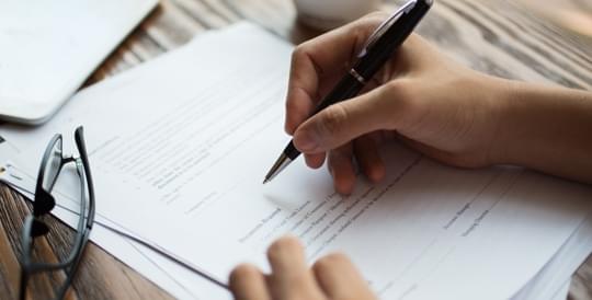 Hand signing a contract - link to SR-22 insurance information from The General Insurance quote page