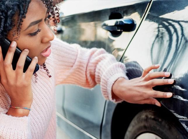 Woman inspecting damage to her car - link to claims information from The General quote page.